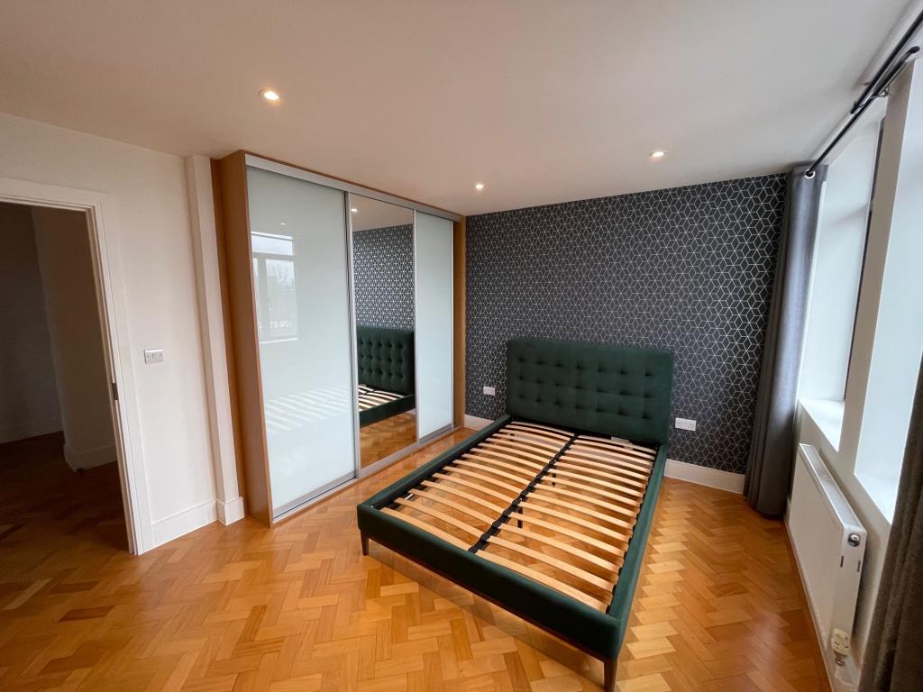 Lot: 102 - ONE-BEDROOM 4TH FLOOR CITY CENTRE APARTMENT - Bedroom with built in sliding wardrobe and parquet wooden flooring